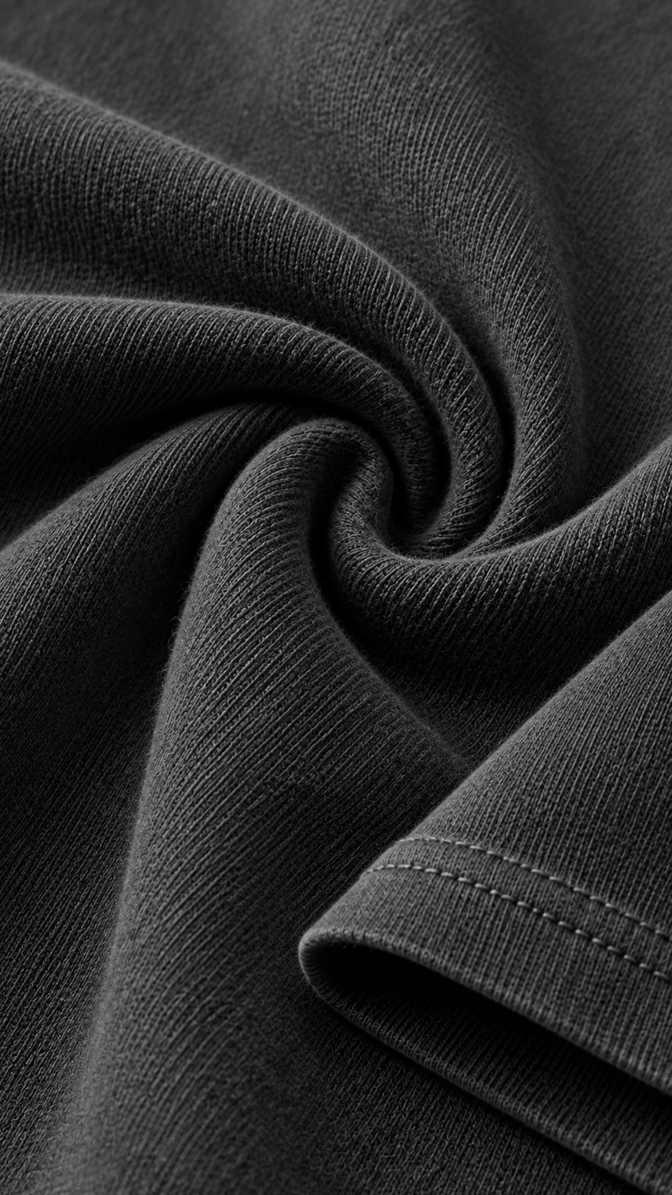 Close-up of dark charcoal gray ribbed fabric with a twisted fold showing the knit texture and hem stitching.